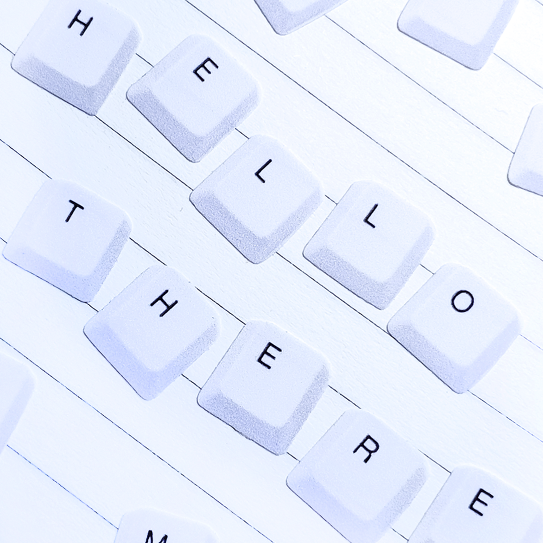 White keyboard keys spelling out the word 'HELLO THERE' on a white wood-textured background.