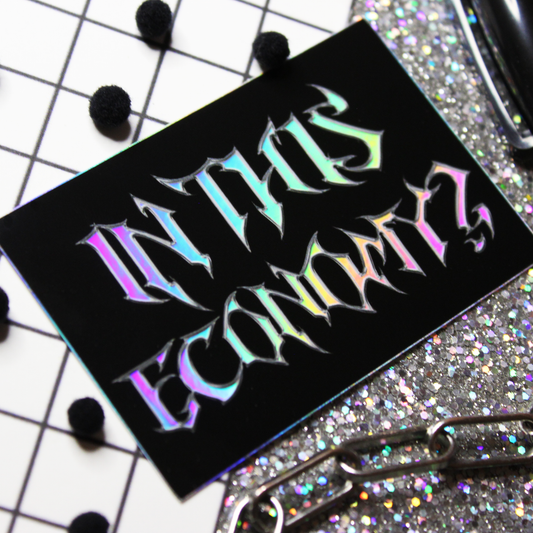 Holographic Metal font sticker with black background that says In this economy.